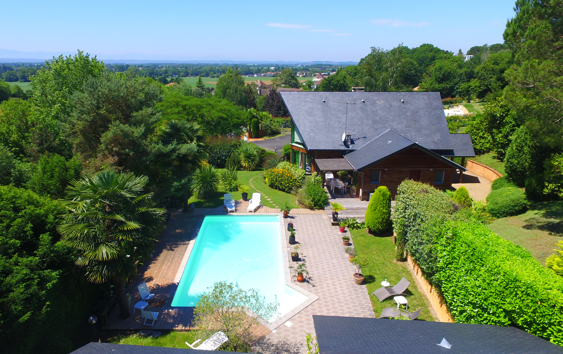 External view of stylish family house with fence, garage, stone driveway and garden, panorama