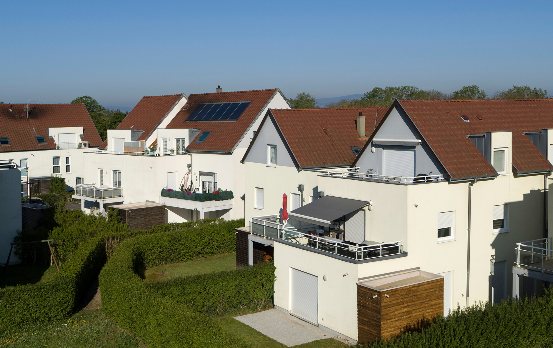 External view of stylish family house with fence, garage, stone driveway and garden, panorama